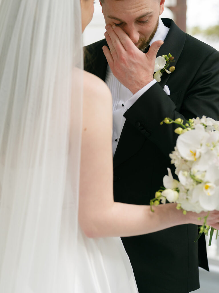 groom wiping tears away during first look