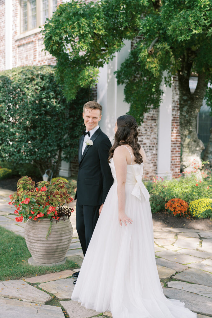 bride and groom smiling and holding hands during first look