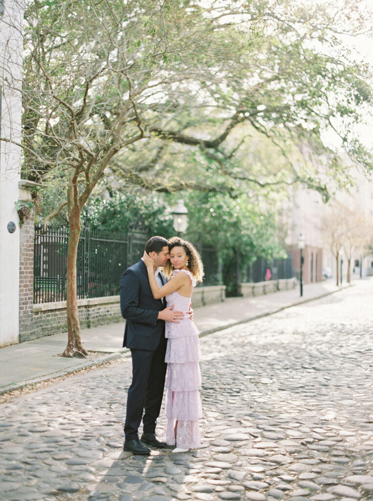 couple embracing on Chalmers Street wit cobblestone - best Charleston Engagement Photo Locations,