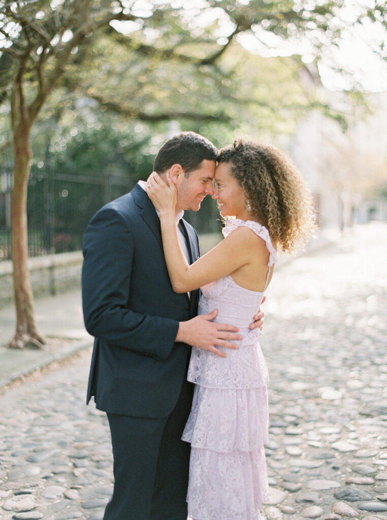 couple embracing on Chalmers Street wit cobblestone - best Charleston Engagement Photo Locations,