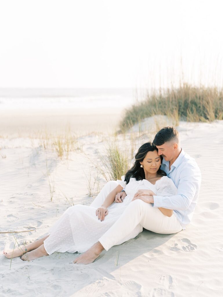 couple sitting in the sand during engagement session at golden hour at Isle of Palm