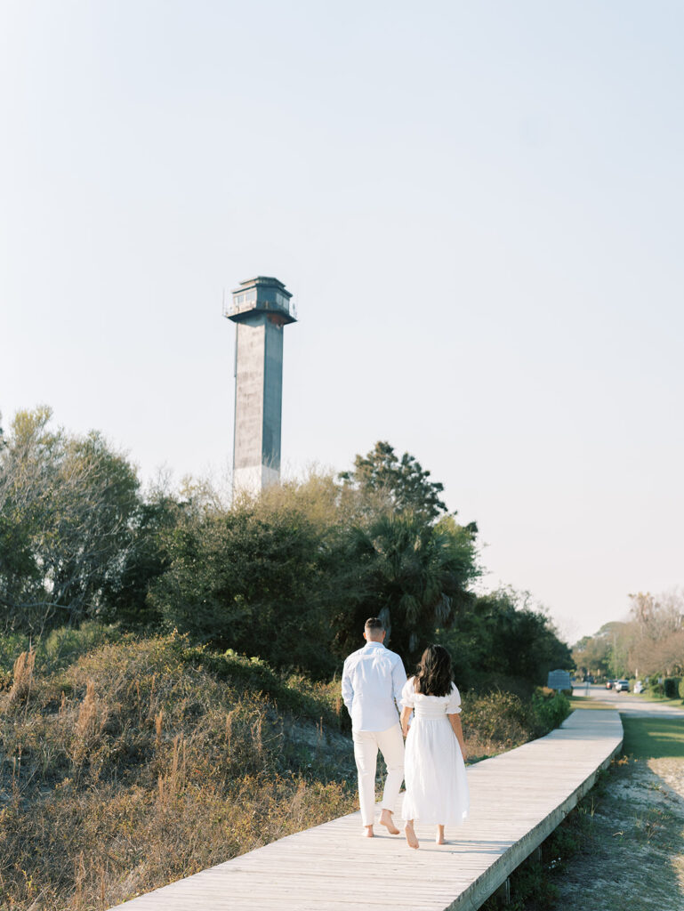 couple holding hands walking on the board walk in Isle of Palm