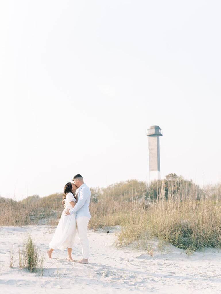 couple kissing infront of the light house and sand dunes at Isle of Palm