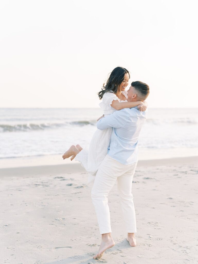 guy picking up fiance at the beach during engagement session, engagement session at Isle of Palm